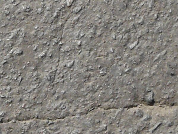Asphalt texture with a grey surface that is very rough vertically through the center, and slightly smoother on either side. Several cracks run through the surface.